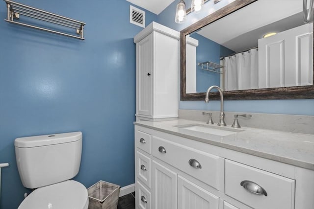 bathroom featuring toilet, baseboards, visible vents, and vanity