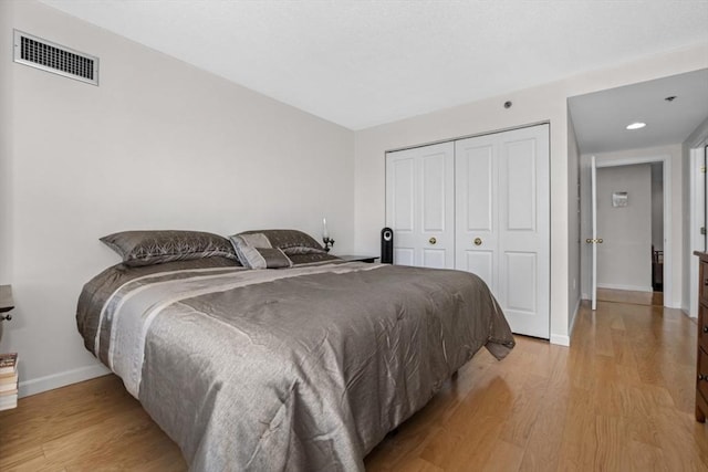 bedroom featuring visible vents, baseboards, a closet, and light wood-type flooring