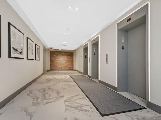 hall featuring elevator, baseboards, and marble finish floor