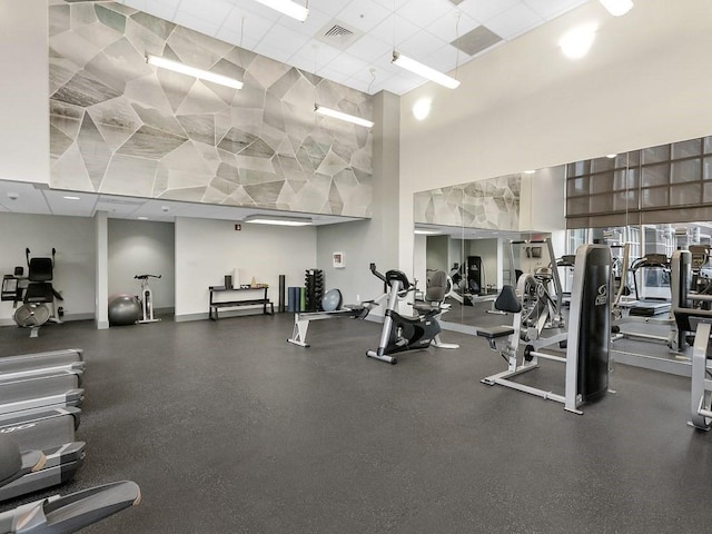 workout area featuring visible vents, a high ceiling, and a drop ceiling