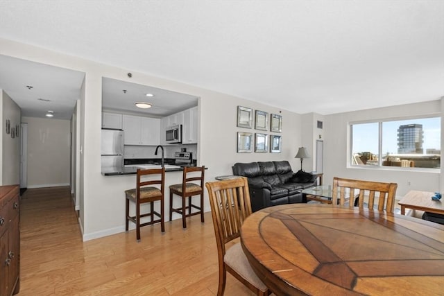 dining space featuring baseboards and light wood-type flooring