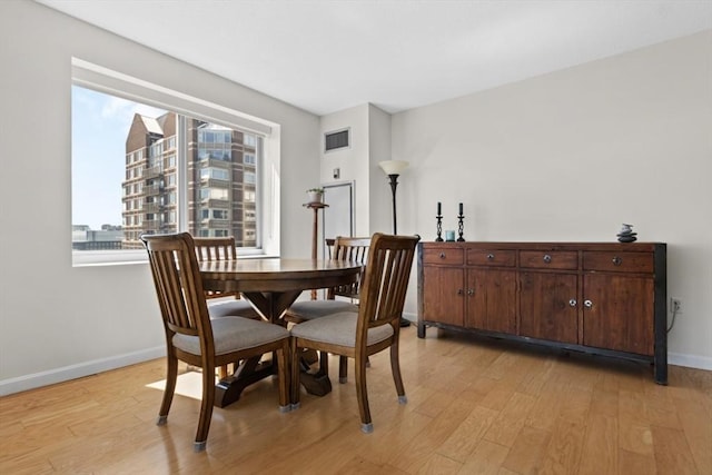 dining area featuring baseboards, light wood-type flooring, and visible vents