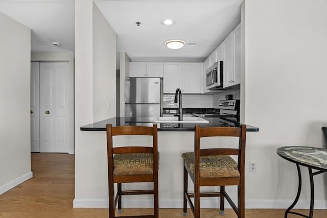 kitchen with dark countertops, white cabinets, stainless steel appliances, and a peninsula