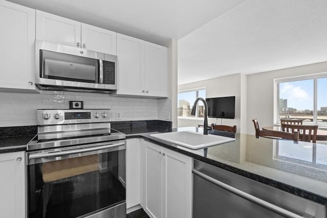 kitchen with a sink, appliances with stainless steel finishes, white cabinets, and tasteful backsplash