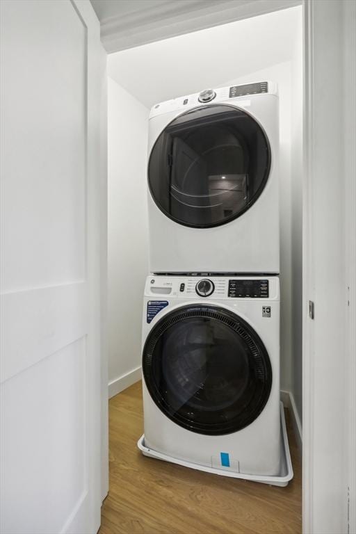 clothes washing area with stacked washer and clothes dryer and hardwood / wood-style flooring