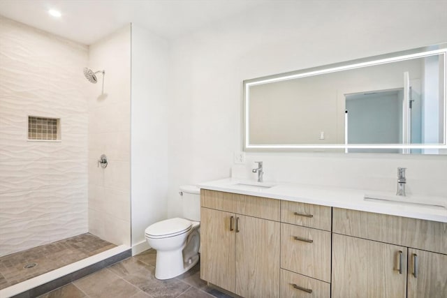 bathroom with tile patterned floors, vanity, toilet, and tiled shower