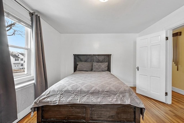 bedroom with radiator, hardwood / wood-style flooring, and multiple windows