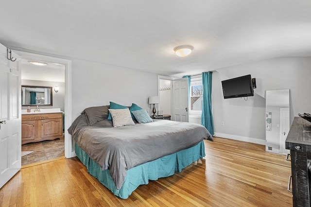 bedroom with sink, connected bathroom, and light hardwood / wood-style floors
