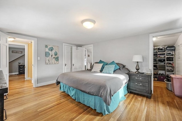 bedroom featuring a walk in closet, a closet, and light hardwood / wood-style flooring