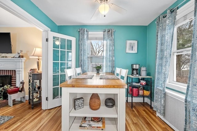 dining space featuring ceiling fan, a fireplace, and light hardwood / wood-style floors