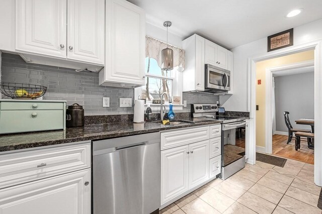 kitchen with sink, white cabinetry, hanging light fixtures, stainless steel appliances, and light tile patterned floors