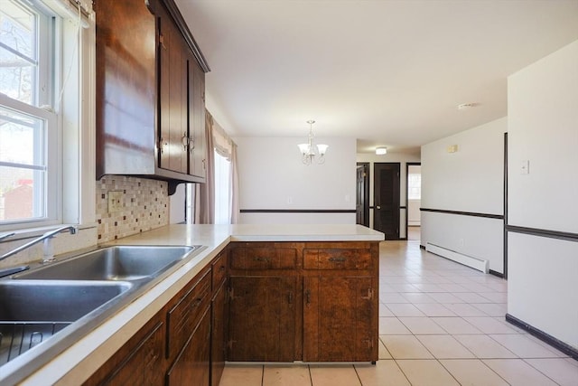 kitchen featuring a sink, plenty of natural light, baseboard heating, and a peninsula
