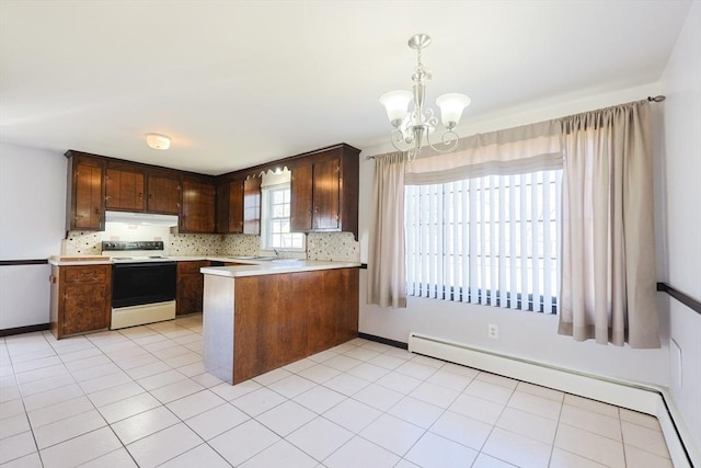 kitchen featuring baseboard heating, light countertops, electric range oven, under cabinet range hood, and a notable chandelier