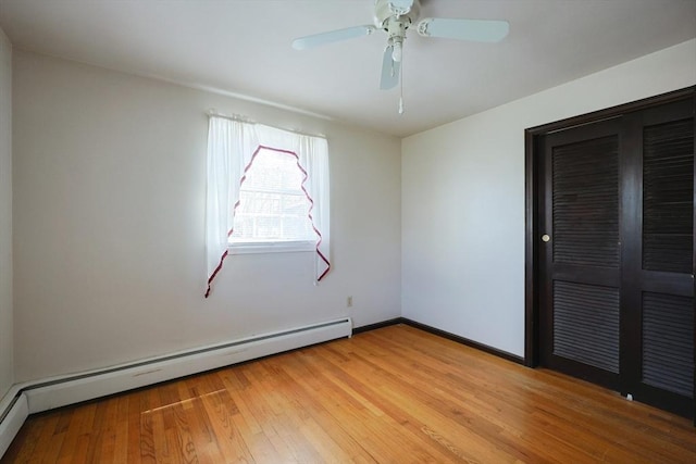 spare room featuring a ceiling fan, baseboards, baseboard heating, and light wood finished floors