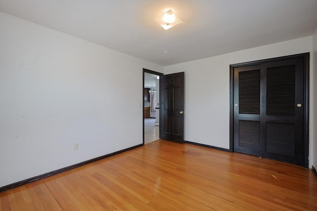 unfurnished bedroom with light wood-type flooring, baseboards, and a closet
