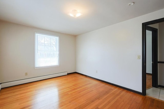 unfurnished room with baseboards, a baseboard heating unit, and light wood finished floors