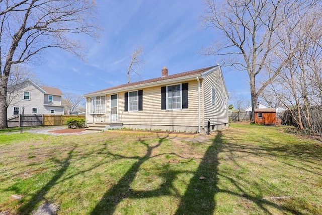 view of front of property with fence, a front lawn, a storage shed, an outbuilding, and a chimney