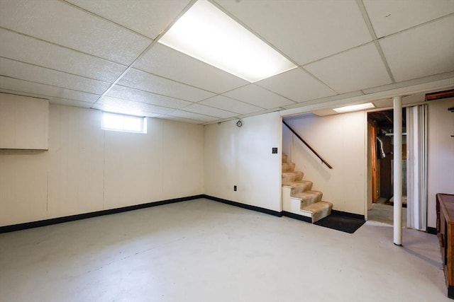 basement featuring stairway, baseboards, and a drop ceiling