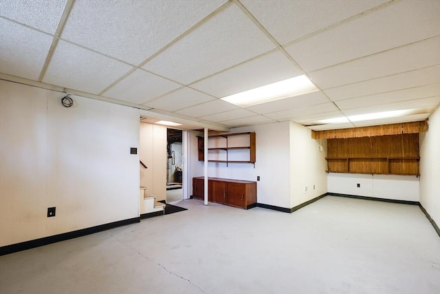finished below grade area with stairs, baseboards, and a paneled ceiling