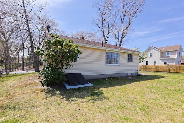 back of property featuring fence, a chimney, and a lawn