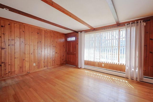 unfurnished room with wooden walls, a baseboard heating unit, beam ceiling, and wood finished floors