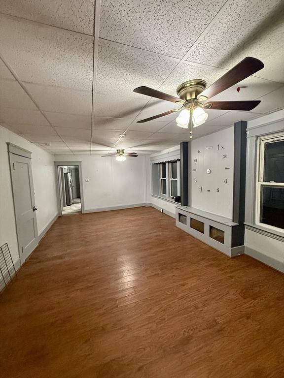 unfurnished room featuring hardwood / wood-style flooring, a drop ceiling, and ceiling fan