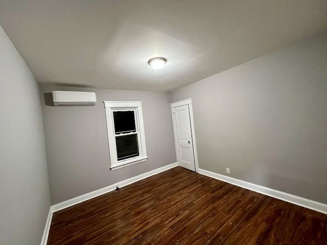 empty room featuring a wall mounted AC and dark hardwood / wood-style flooring