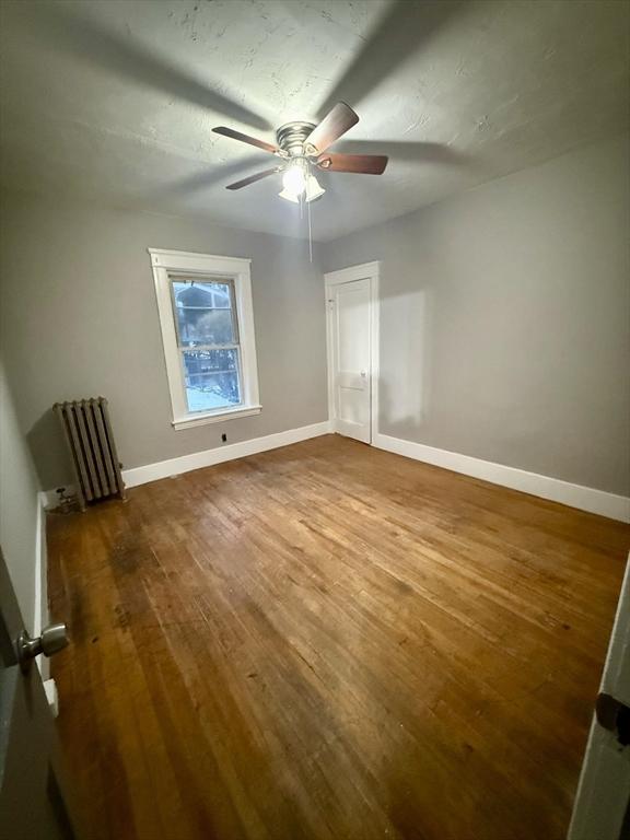 interior space with ceiling fan, radiator, wood-type flooring, and a textured ceiling