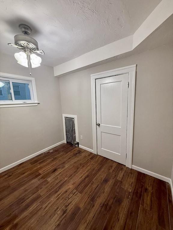 interior space with a textured ceiling, dark wood-type flooring, and ceiling fan