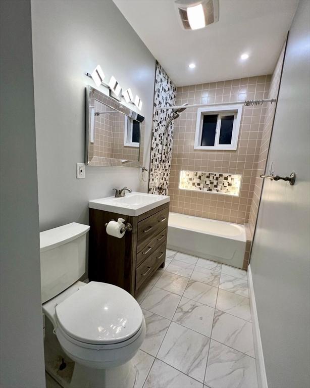 full bathroom with toilet, tiled shower / bath, and vanity