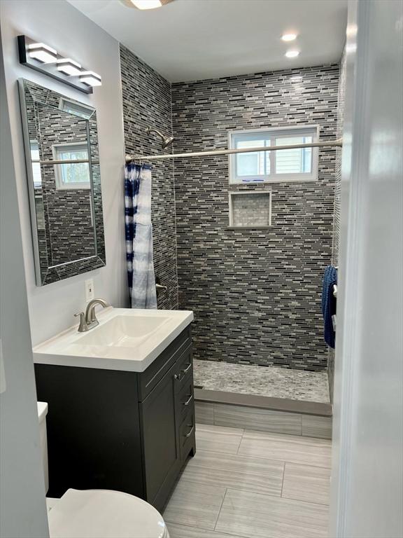 bathroom featuring toilet, vanity, a wealth of natural light, and a shower with shower curtain