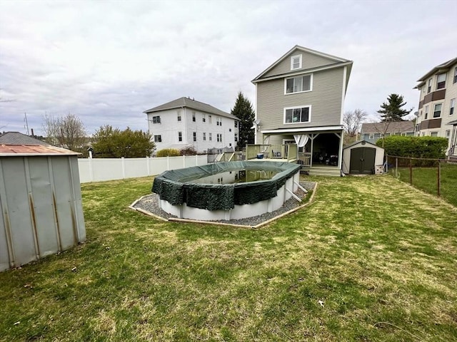 rear view of house with a covered pool, a yard, and a storage unit