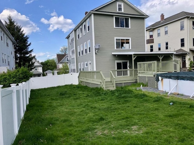 rear view of property with a pool side deck and a yard