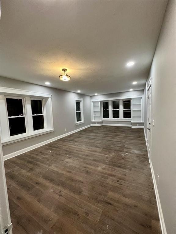 unfurnished living room with built in features and dark hardwood / wood-style flooring