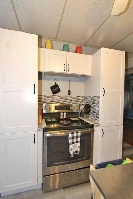 kitchen featuring white cabinetry, backsplash, a drop ceiling, and stainless steel range with electric stovetop