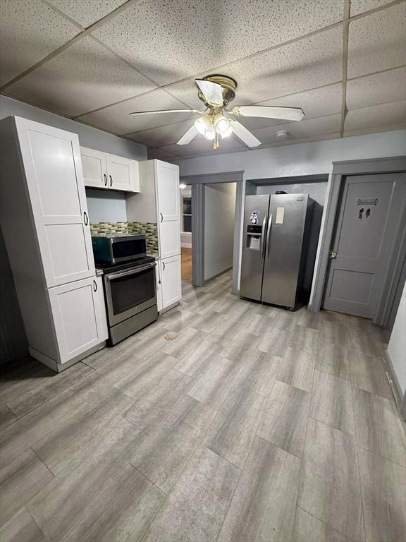 kitchen featuring ceiling fan, white cabinets, a drop ceiling, and appliances with stainless steel finishes