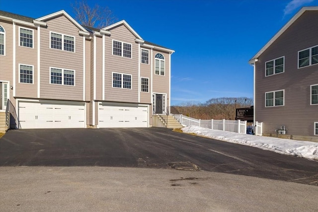 view of front of home with a garage, driveway, and fence