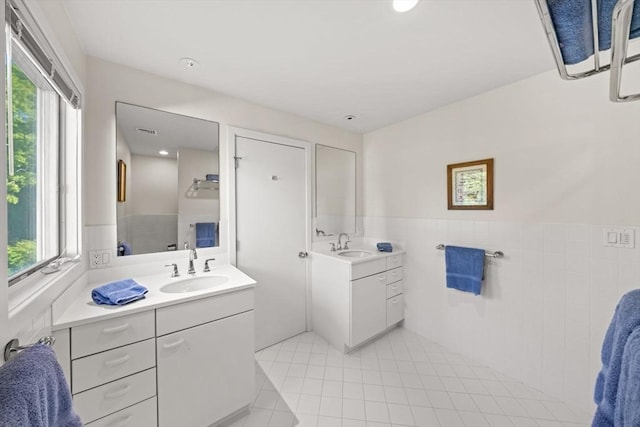 124 William St, Dartmouth, MA 02748 - bathroom featuring tile patterned flooring, two vanities, tile walls, healthy amount of natural light, and a wainscoted wall