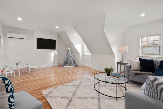 living room with wood-type flooring, a wall mounted AC, and plenty of natural light