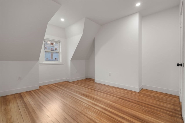 additional living space with light wood-type flooring and lofted ceiling