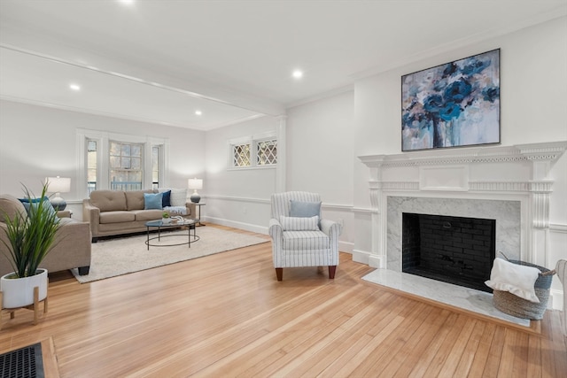 living room featuring hardwood / wood-style floors, crown molding, and a fireplace