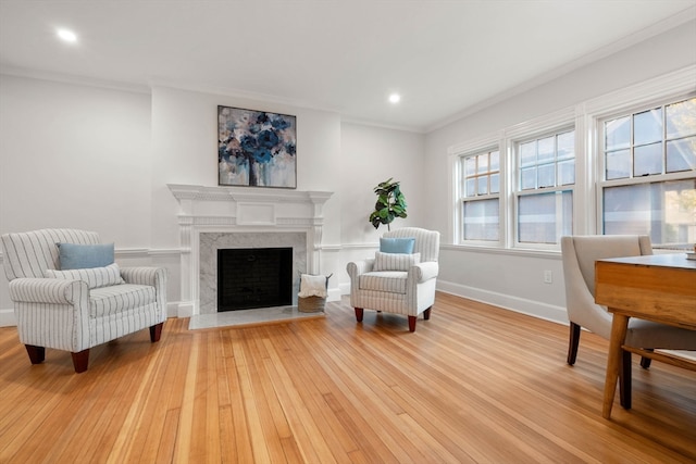 living area featuring light hardwood / wood-style floors, a high end fireplace, and ornamental molding