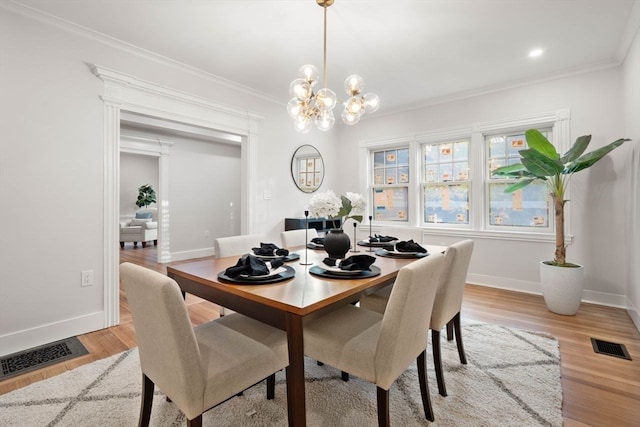 dining space featuring light wood-type flooring, a notable chandelier, and crown molding