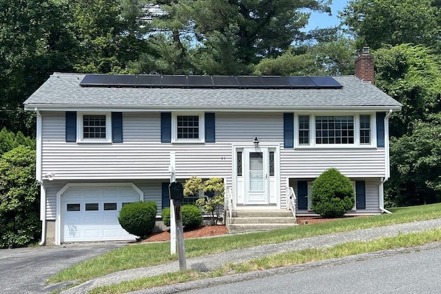 31 Dix Rd, Woburn, MA 01801 - bi-level home featuring a chimney, solar panels, an attached garage, asphalt driveway, and a shingled roof