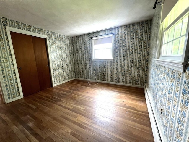 31 Dix Rd, Woburn, MA 01801 - unfurnished bedroom featuring wallpapered walls, wood finished floors, a closet, and a baseboard radiator