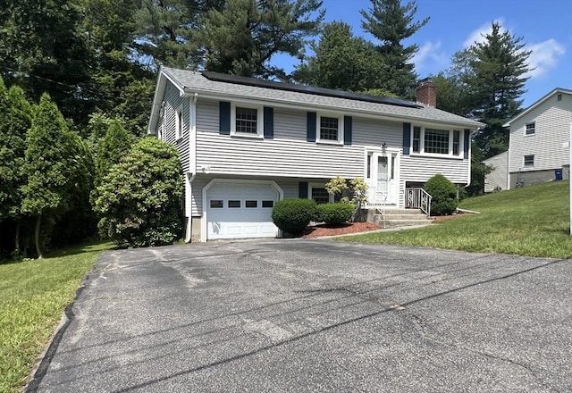 31 Dix Rd, Woburn, MA 01801 - bi-level home with a chimney, solar panels, a front lawn, driveway, and a garage