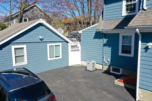 73 Harold St, Milton, MA 02186 - view of side of property featuring roof with shingles, central AC, and a patio area