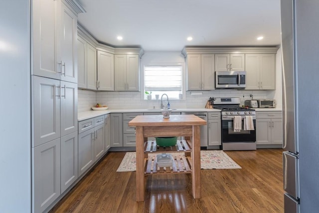 73 Harold St, Milton, MA 02186 - kitchen featuring appliances with stainless steel finishes, a sink, gray cabinetry, light countertops, and decorative backsplash