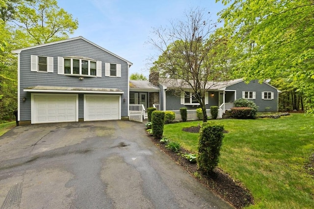 view of front of home with a porch, driveway, an attached garage, and a front lawn