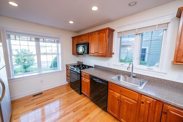 31 Mulligan Dr Unit 31, Weymouth, MA 02190 - kitchen featuring black appliances, light wood-style floors, recessed lighting, brown cabinetry, and estacked washer and dryer
